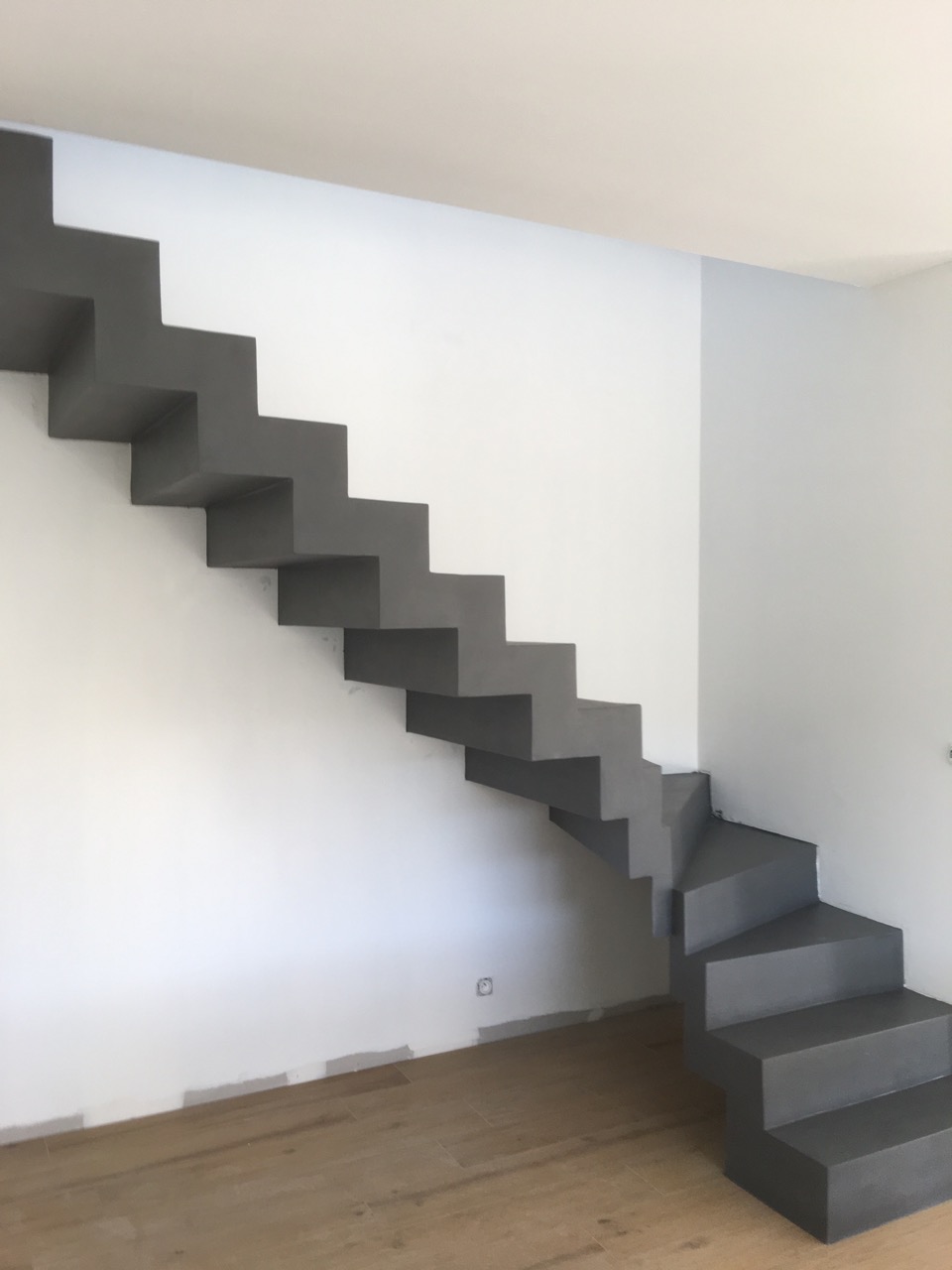 splendide escalier crémaillère dans une pièce à vivre en béton ciré couleur alchimie aureville pour un maitre d'œuvre