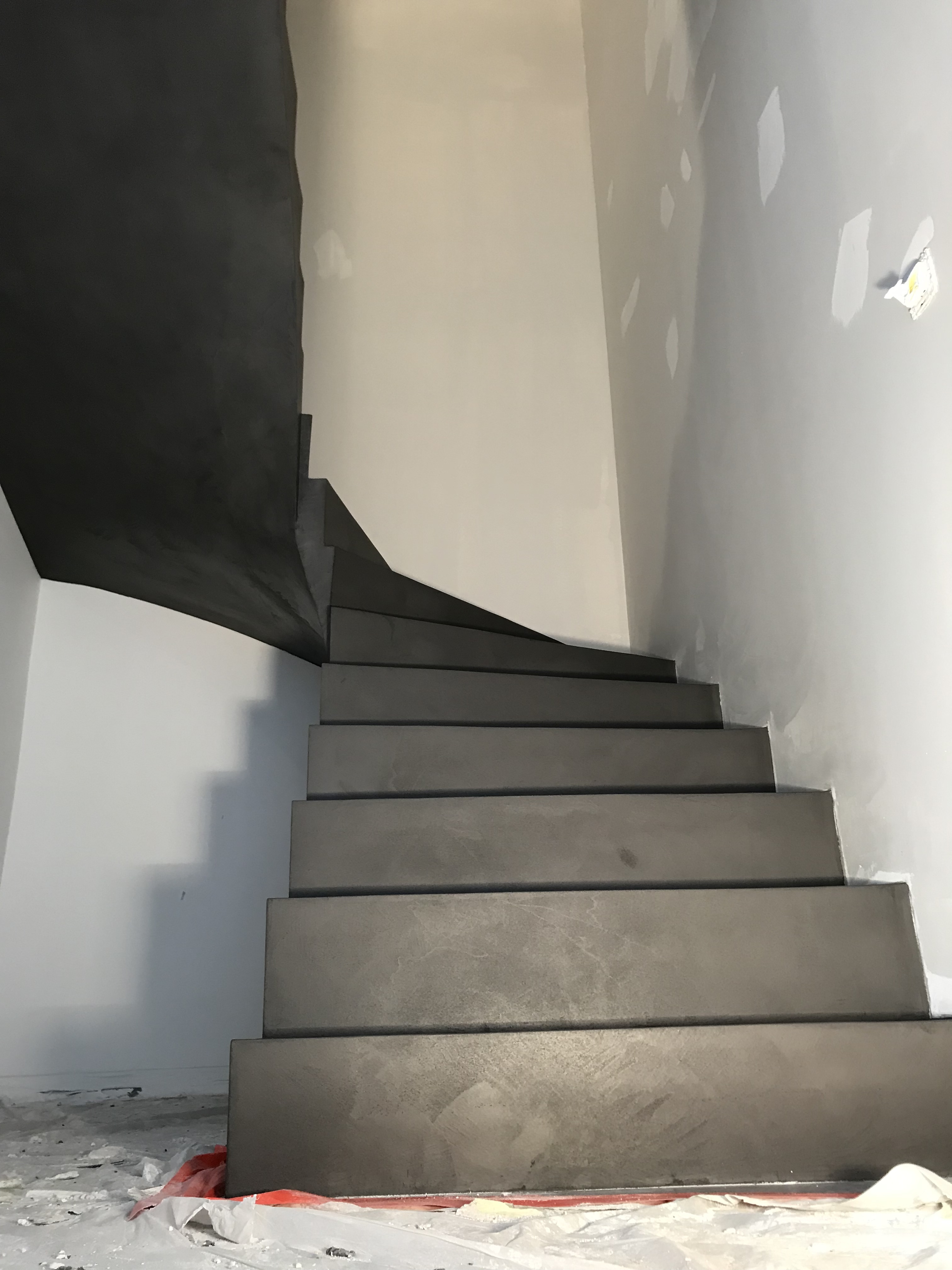 superbe escalier à paillasse deux quart tournant en béton ciré couleur gris orbital pour un constructeur