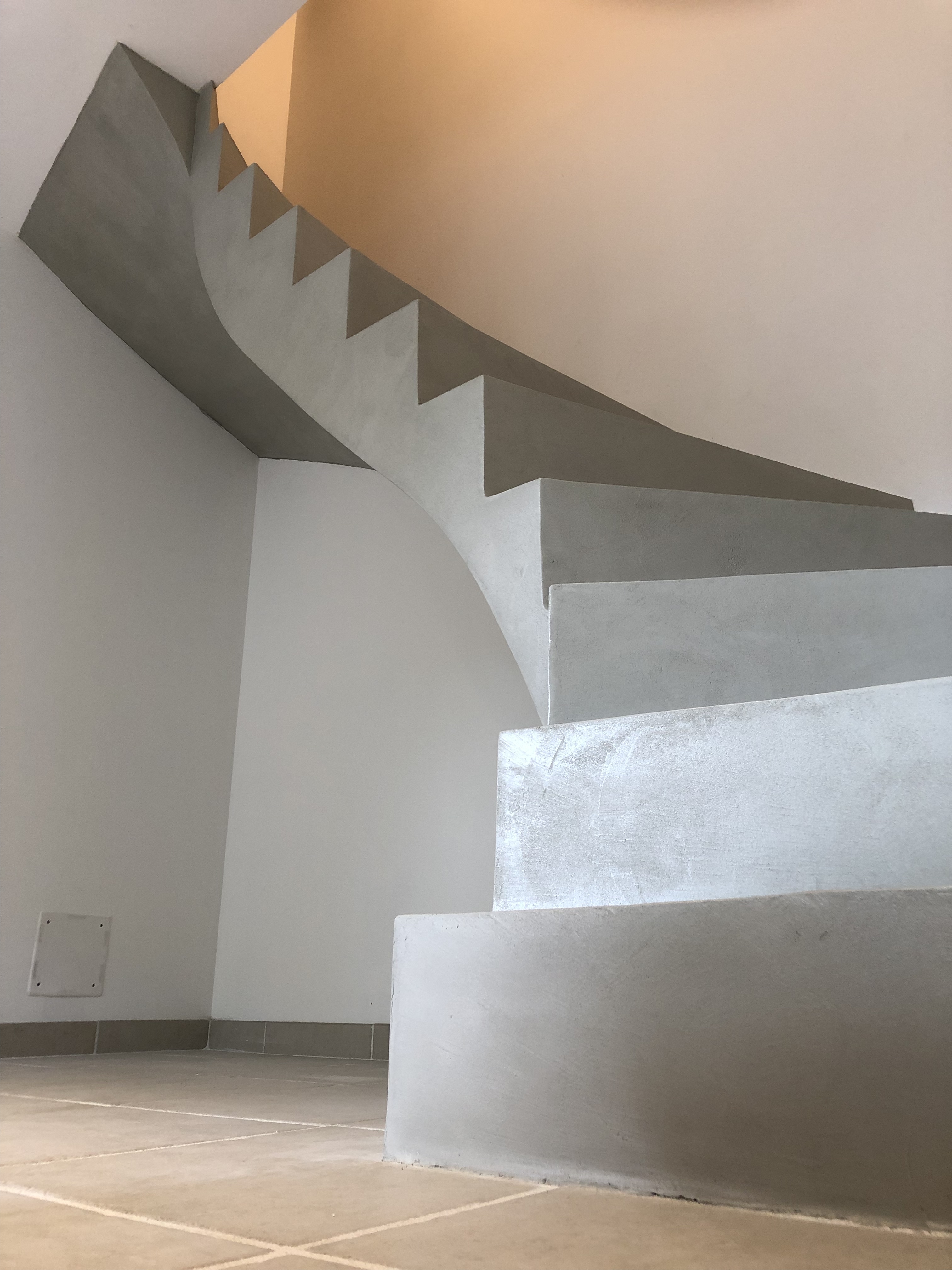 audacieux escalier à paillasse deux quart tournant en béton ciré vernis soyeux couleur gris perle à Royan en Charente maritime dans la région nouvelle aquitaine pour un particulier