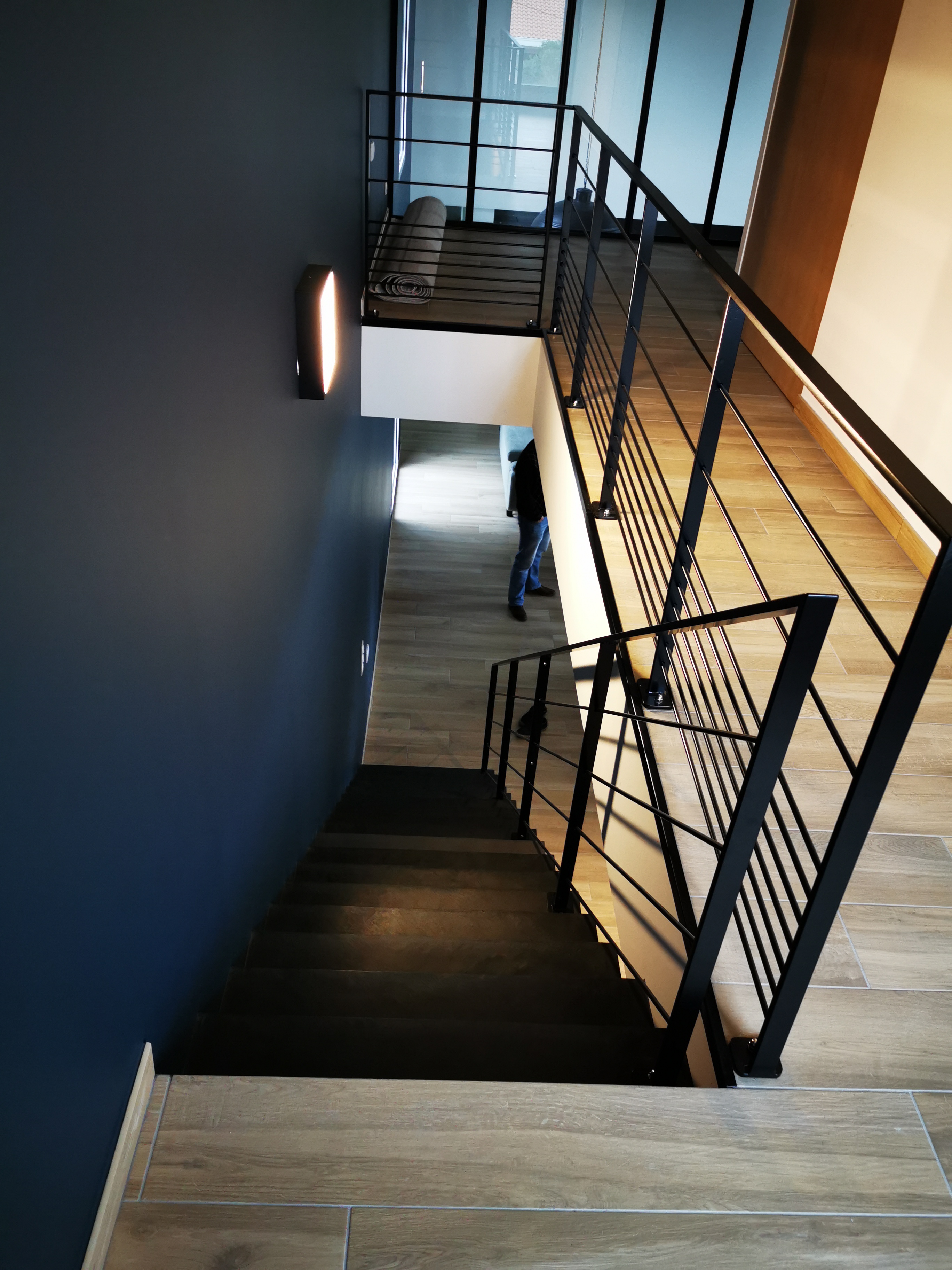 Descente d'un escalier en béton ciré avec garde corps en fer forgé noir