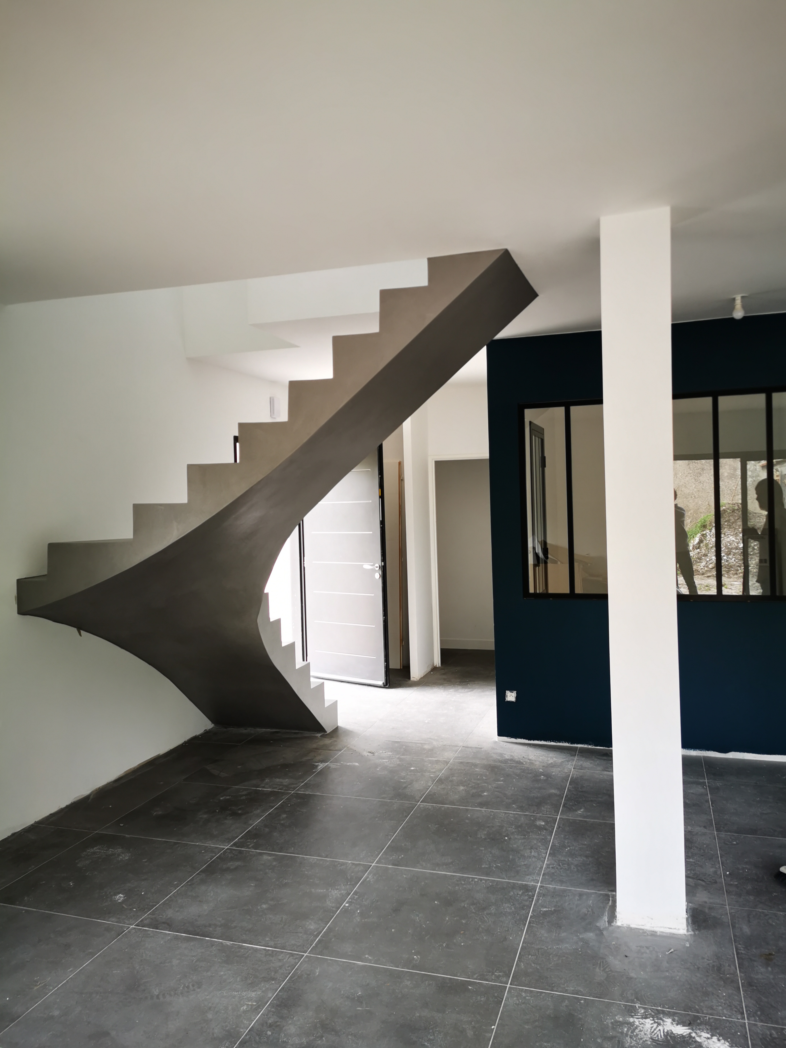 Belle intégration d'un escalier balancé séparant l'entrée de la maison et le salon tout en gardant l'espace