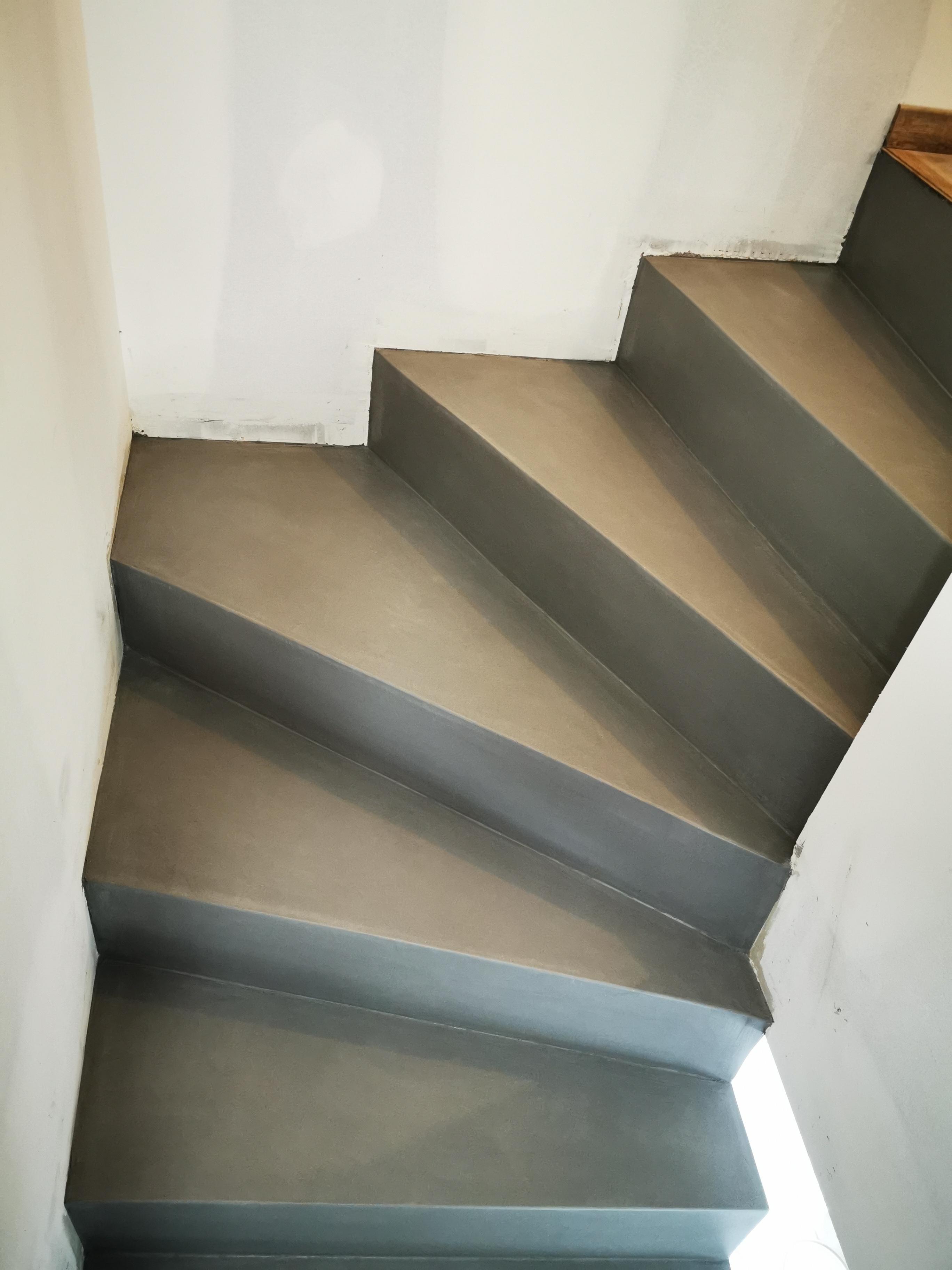 Béton ciré gris sur les marches balancées d'un escalier confortable dans une maison individuelle