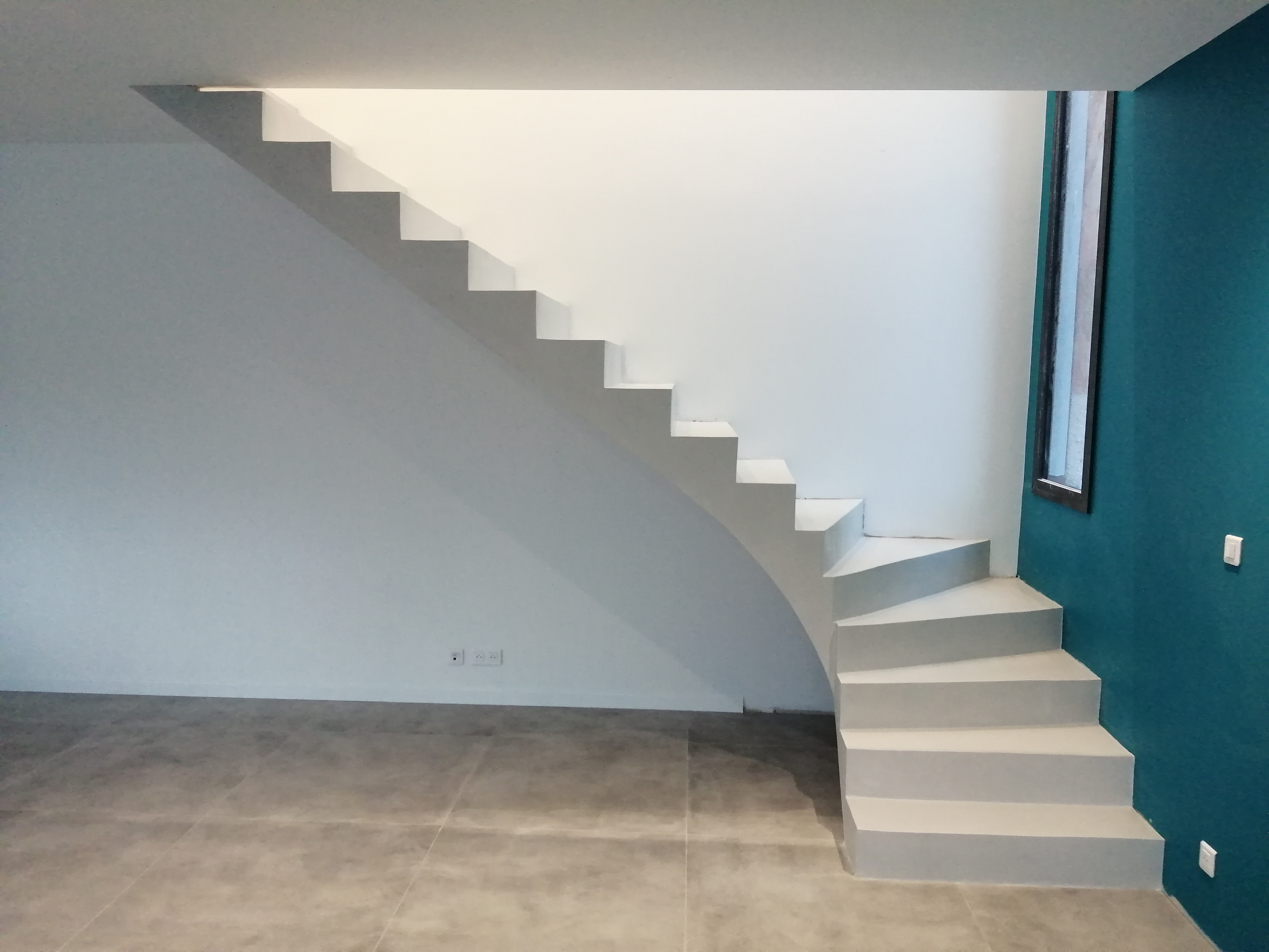 Escalier béton à paillasse un quart balancé en bas avec un revêtement béton ciré gris cendré