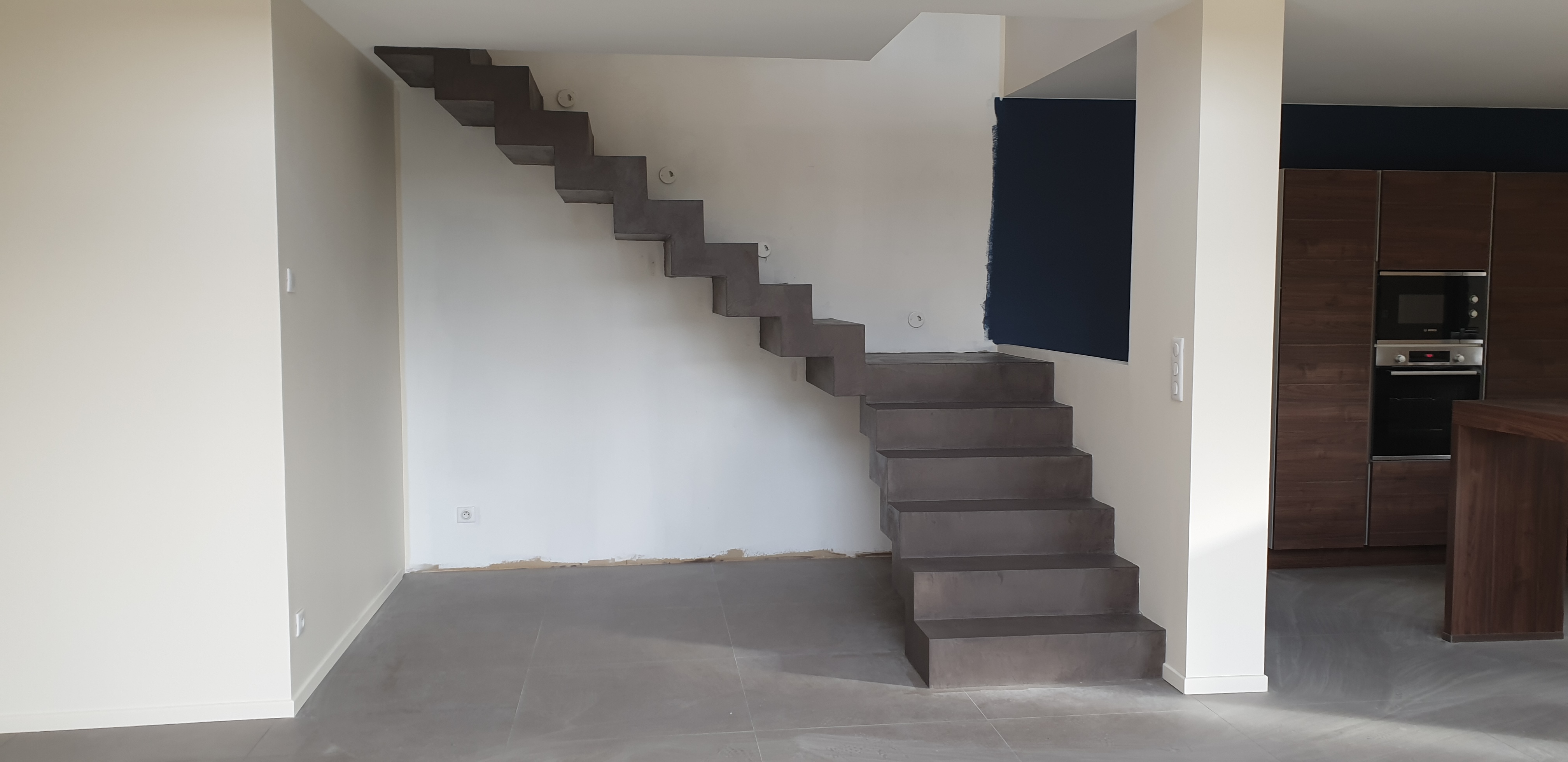 Application d'un béton ciré couleur Nubuck sur un escalier sur fond d'un mur blanc