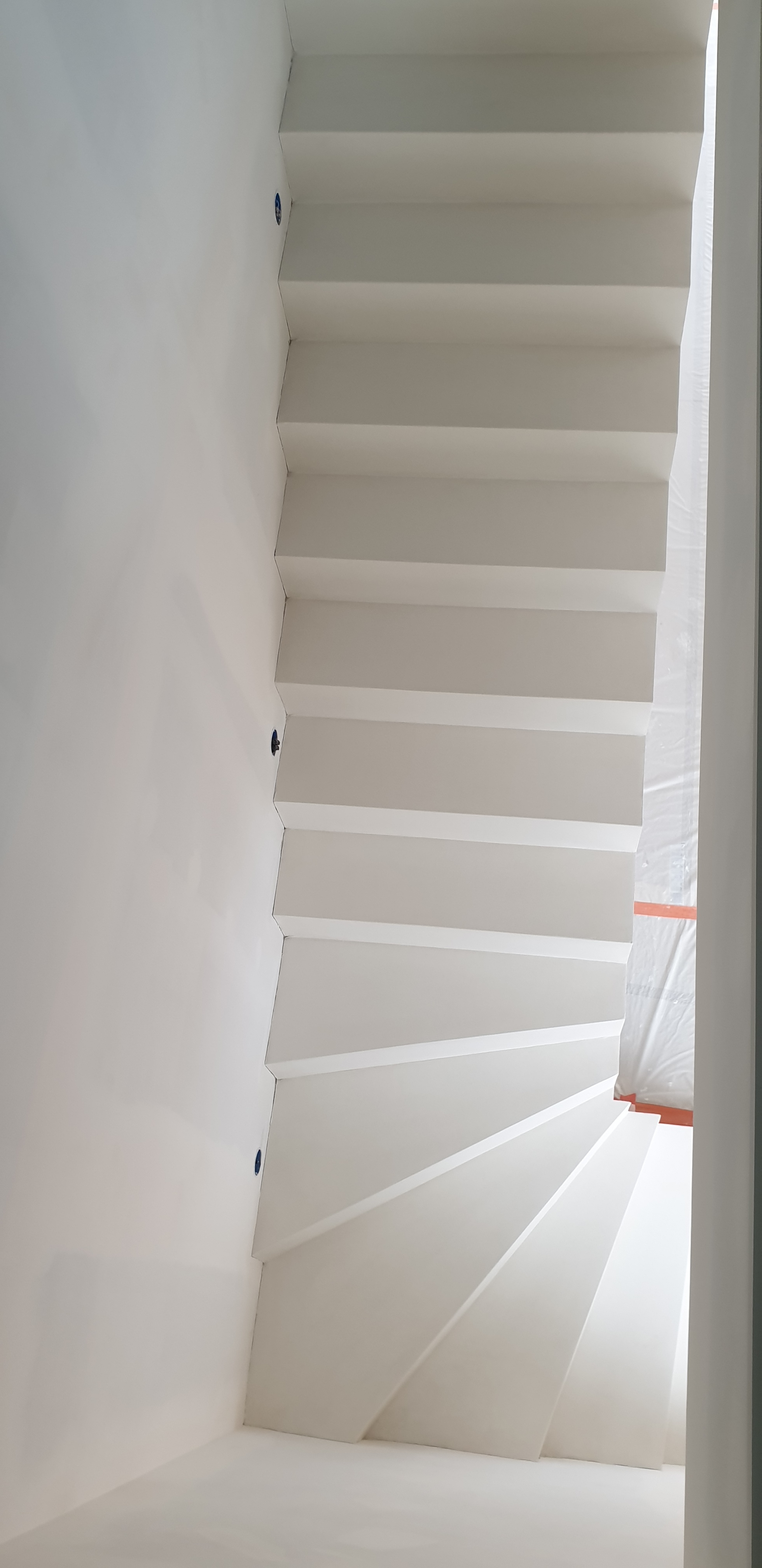 Application d'un béton ciré blanc everest sur un escalier un quart tournant dans une maison individuelle à Viriat