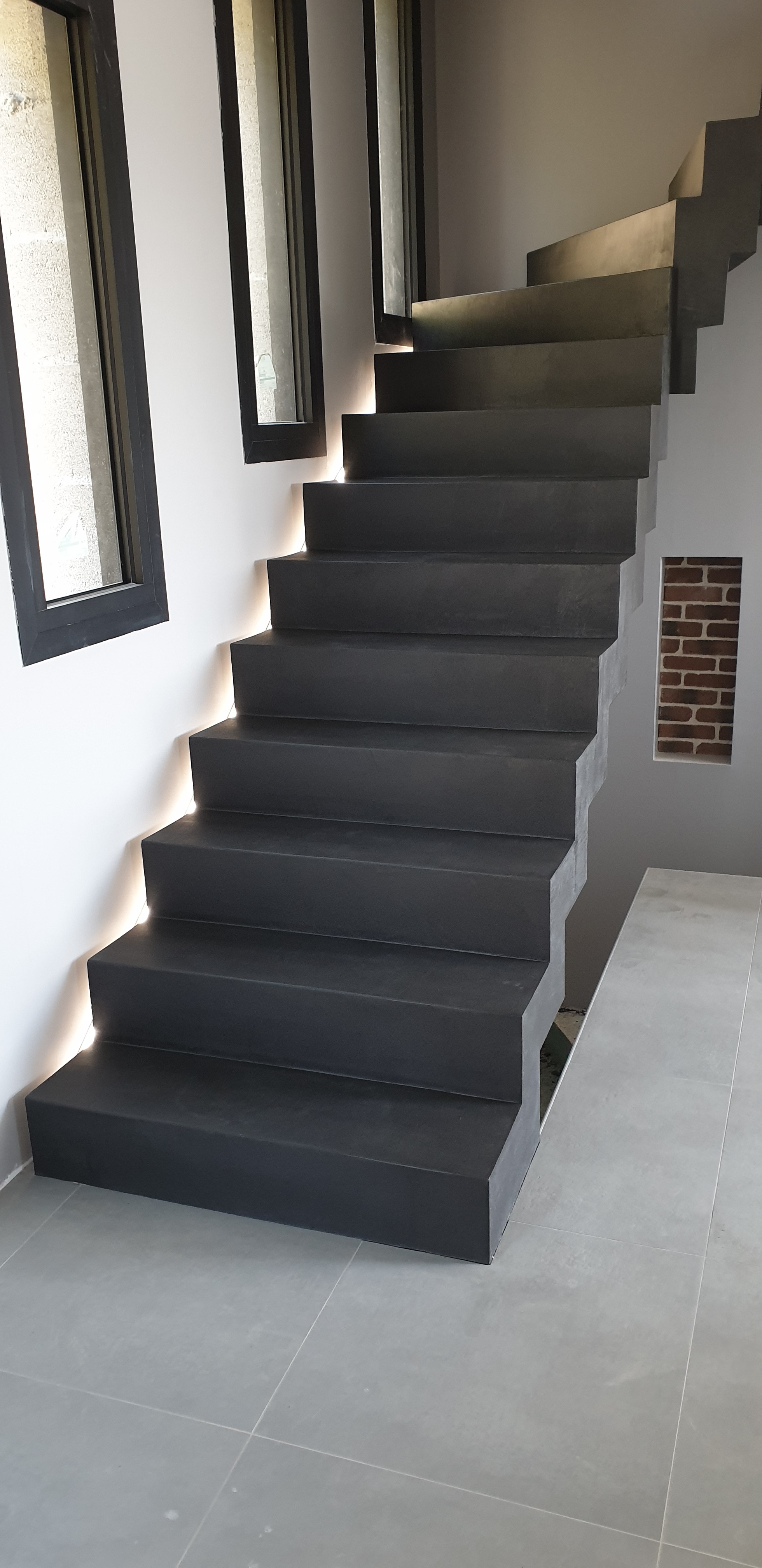 Application d'un béton ciré gris anthracite sur un escalier moderne décollé du mur