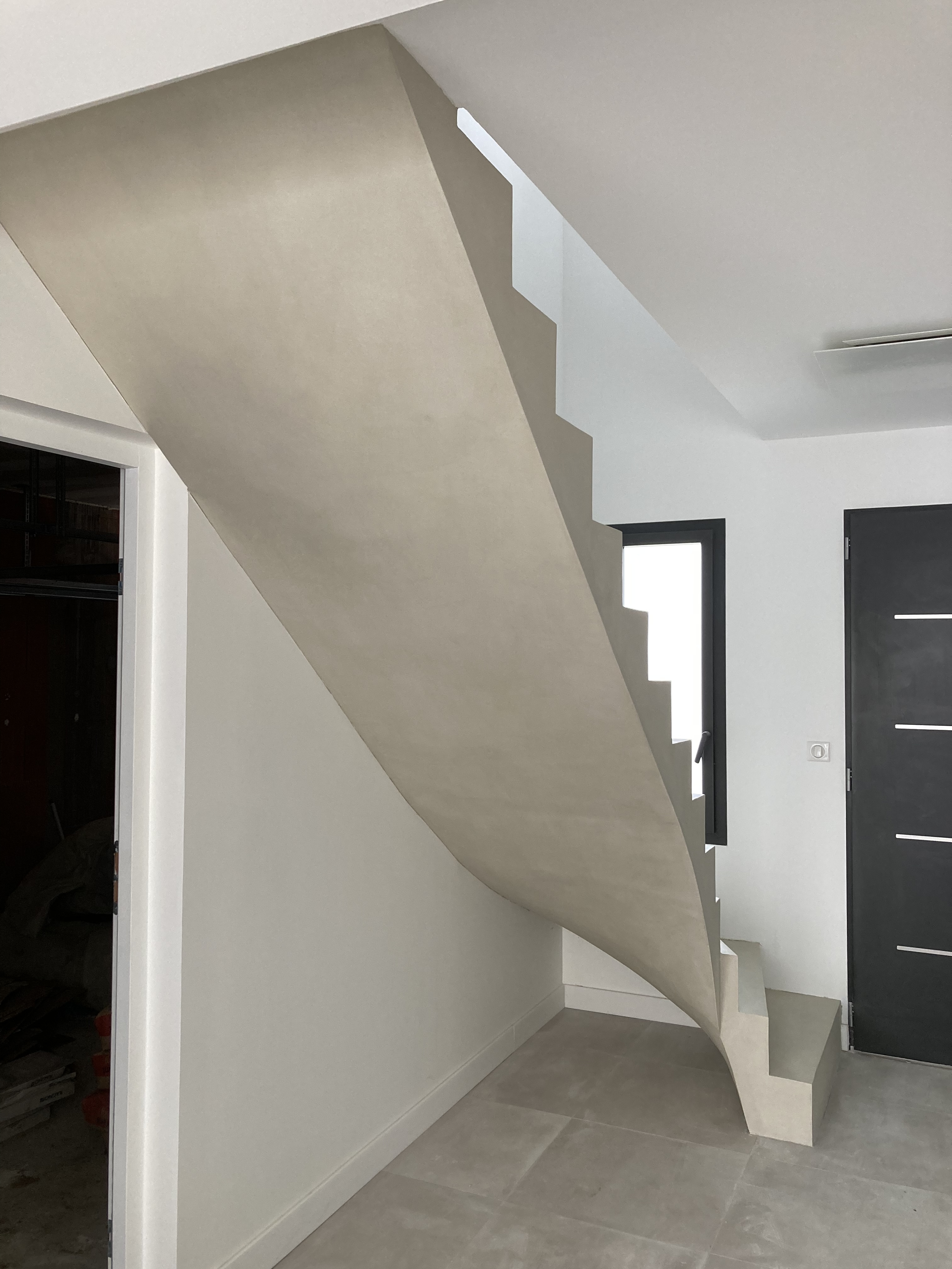 Dessous d'un escalier avec revêtement béton ciré dans une maison individuelle en Aquitaine