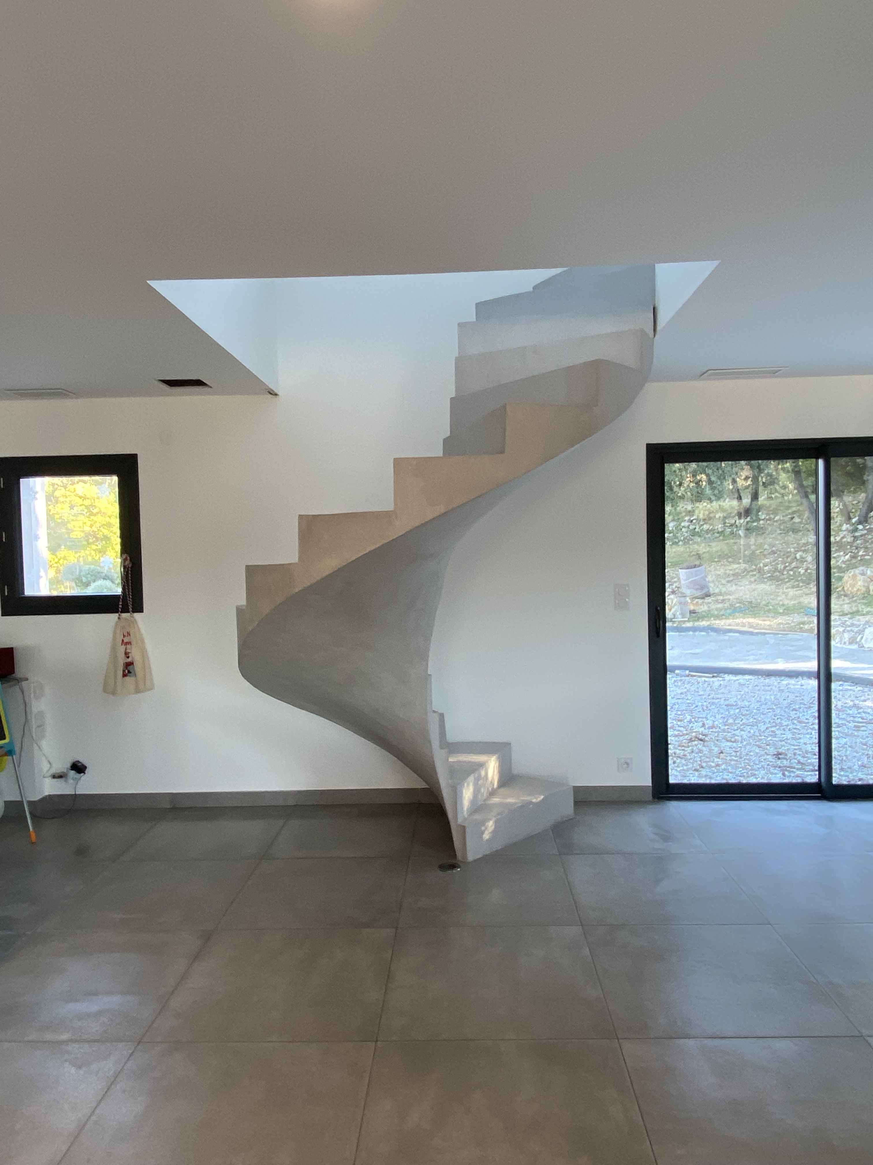 Escalier hélicoïdal dans une maison fini, dont la couleur du béton ciré est en zinc, réalisé par Jean De Pastors.